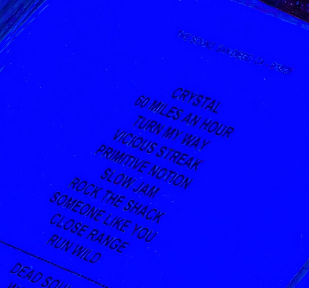 A list of song titles printed in white text on a blue background, featuring titles such as 'Crystal', '60 Miles an Hour', and 'Run Wild'.
